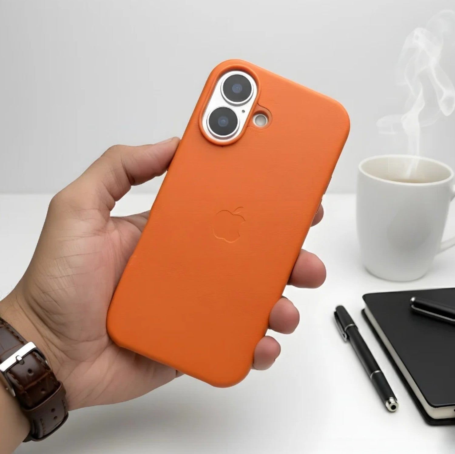 Hand holding a orange leather MagSafe case for iPhone.