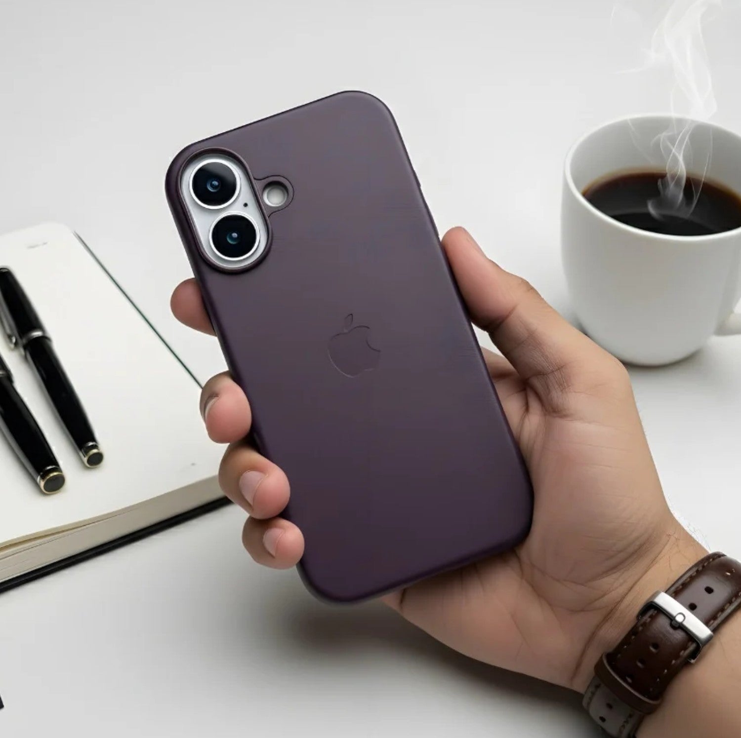 Hand holding a plum leather MagSafe case for iPhone.