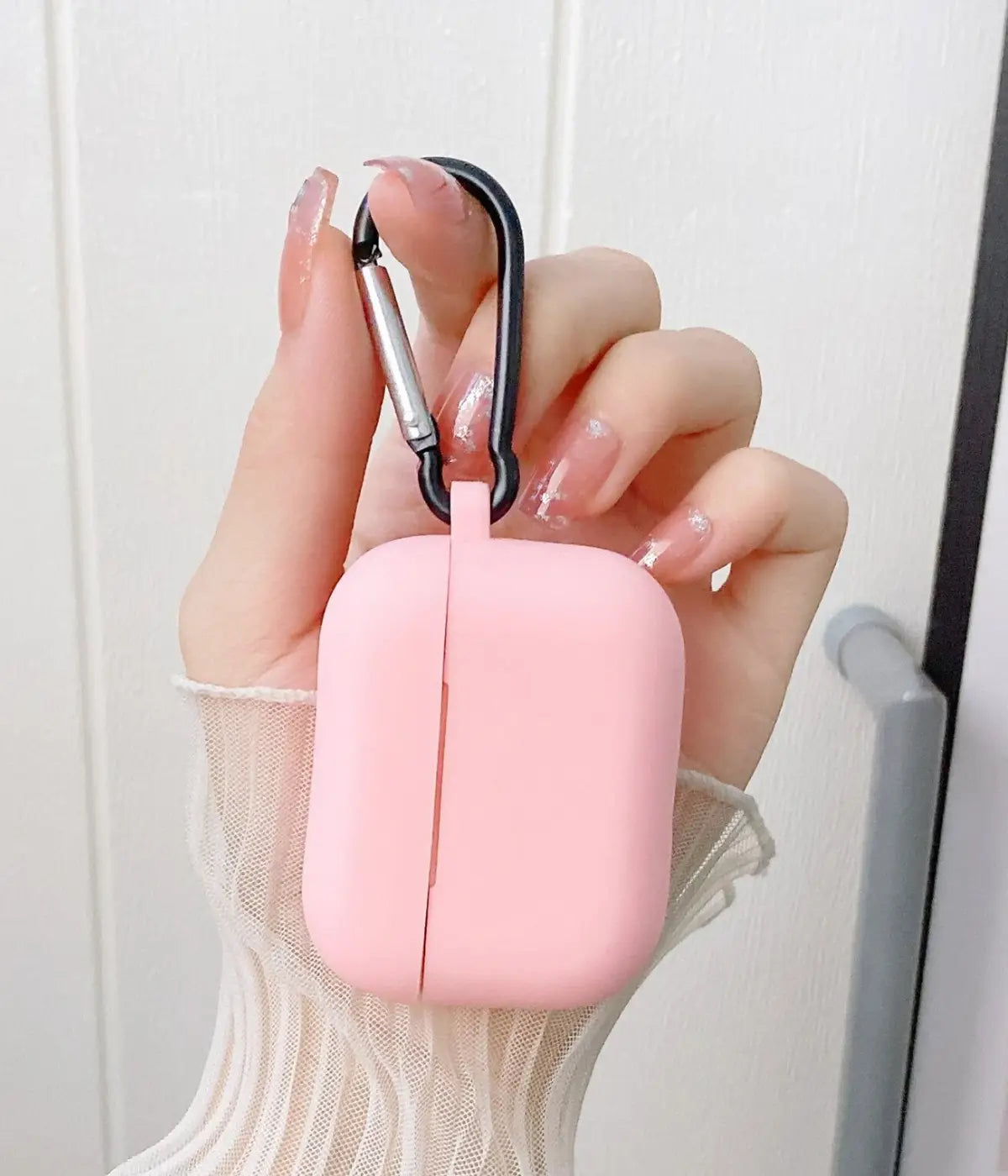 Cameo Pink airpods case with carabiner held by a hand.