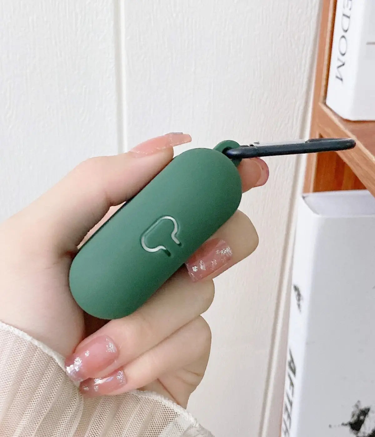 Close-up of a Cyprus Green liquid silicone protective case for Apple AirPods held in a hand