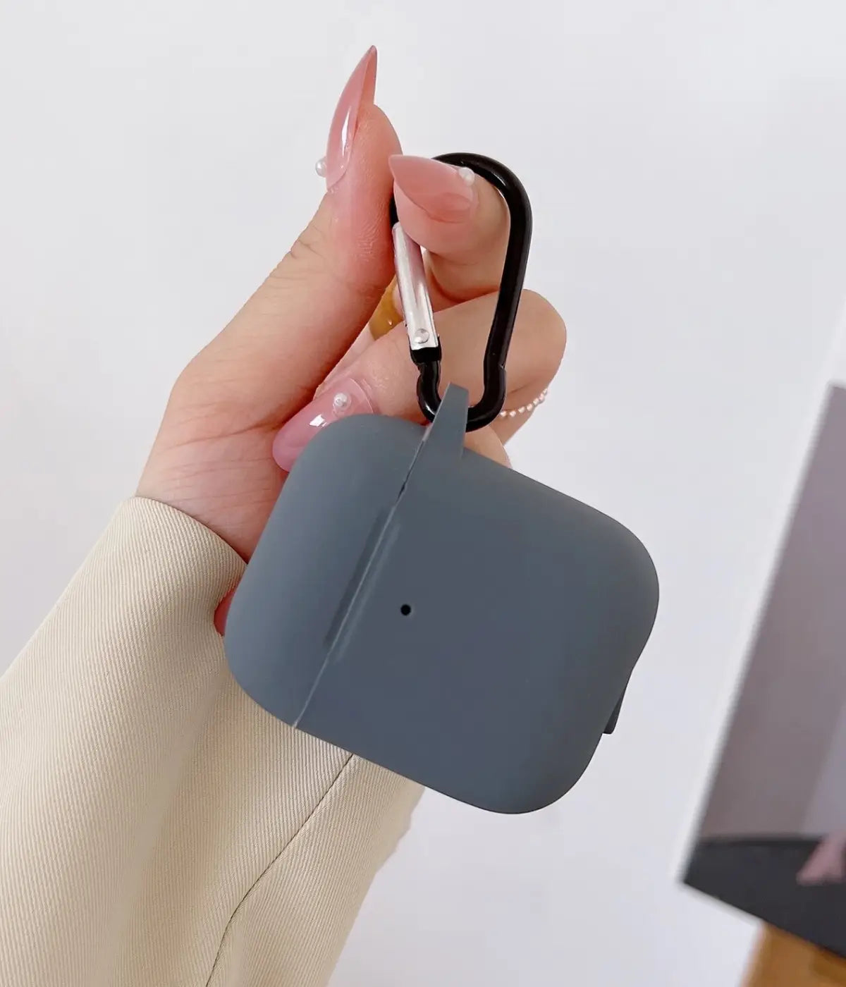 Dark Grey airpods case with carabiner held by a hand.