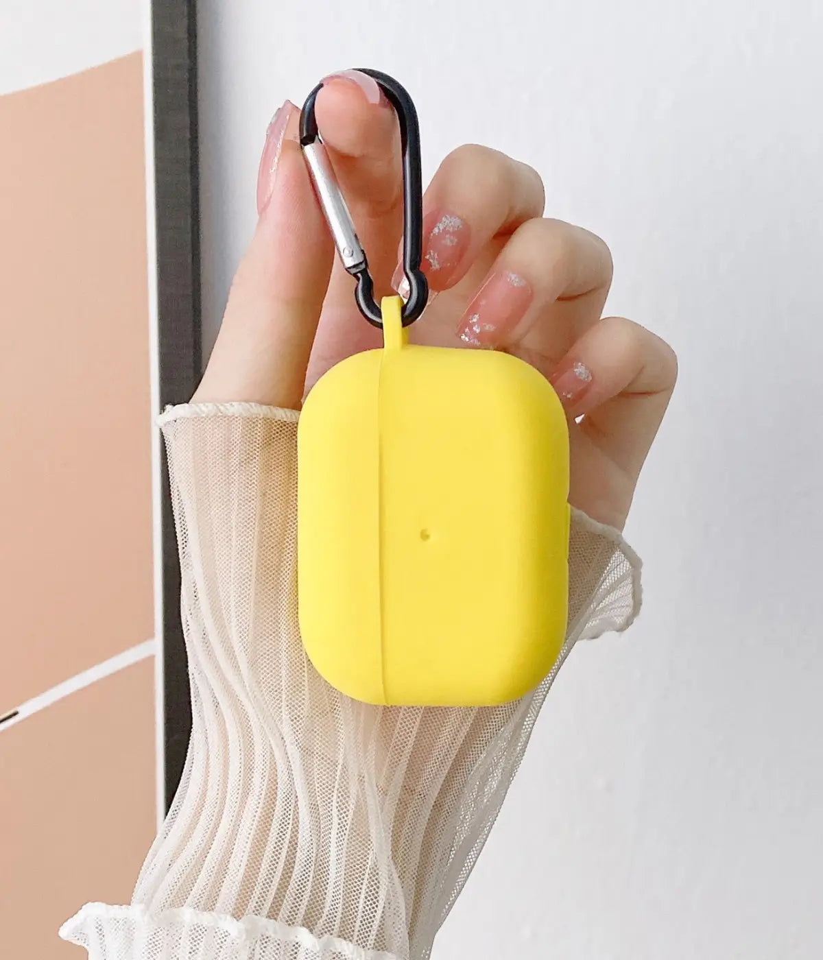 Yellow airpods case with carabiner held by a hand.