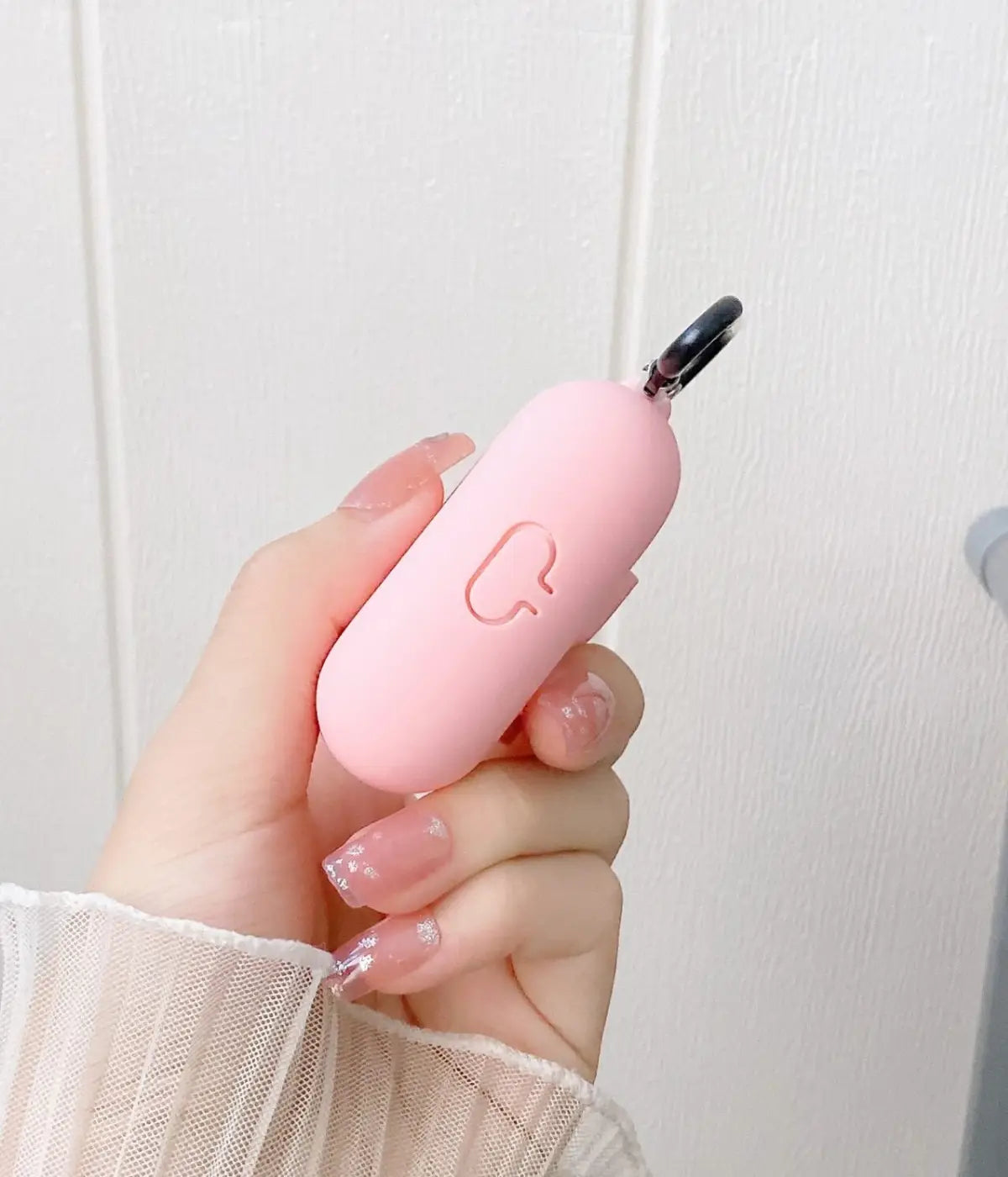 Close-up of a Cameo Pink liquid silicone protective case for Apple AirPods held in a hand