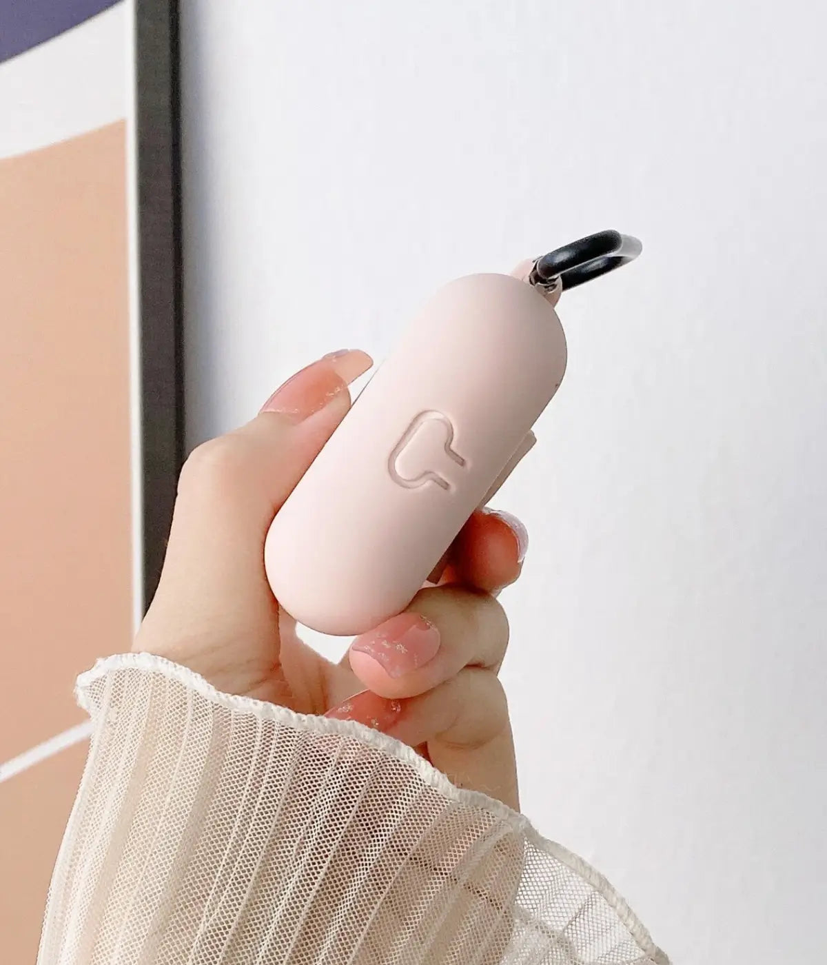 Close-up of a Sand Pink liquid silicone protective case for Apple AirPods held in a hand