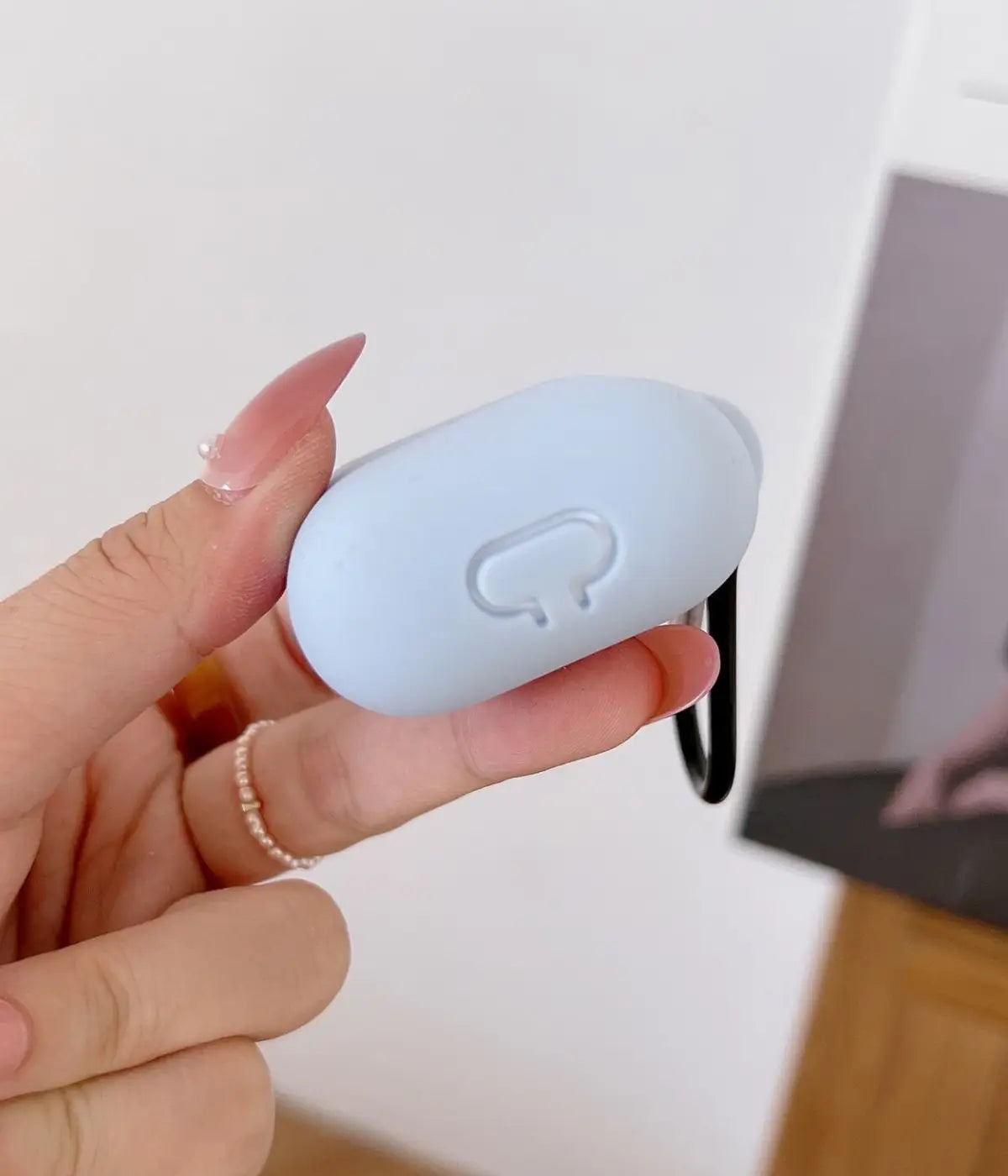 Sky Blue airpods case with carabiner held by a hand.