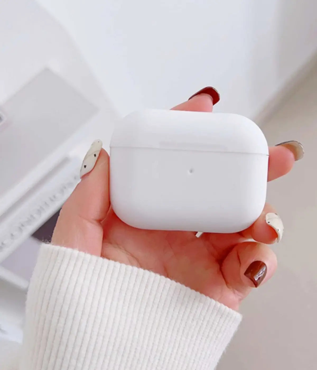White airpods case with carabiner held by a hand.