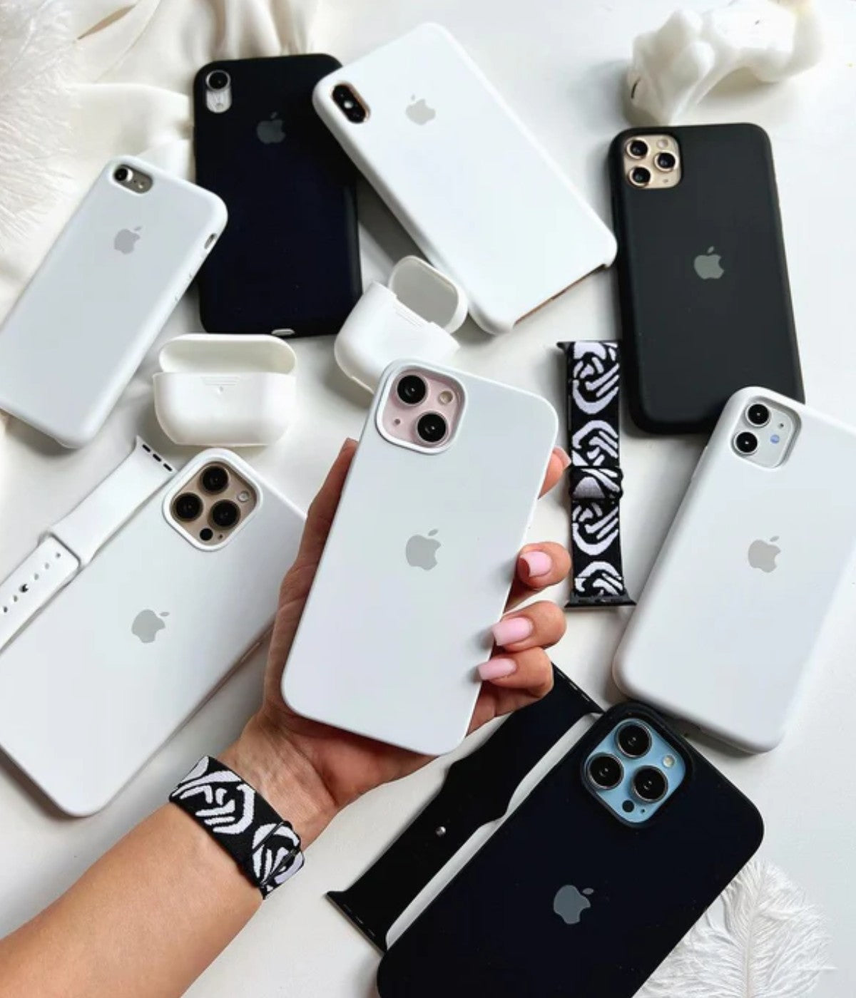 White iPhone silicone cases held by a hand on a white surface.