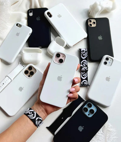 White iPhone silicone cases held by a hand on a white surface.