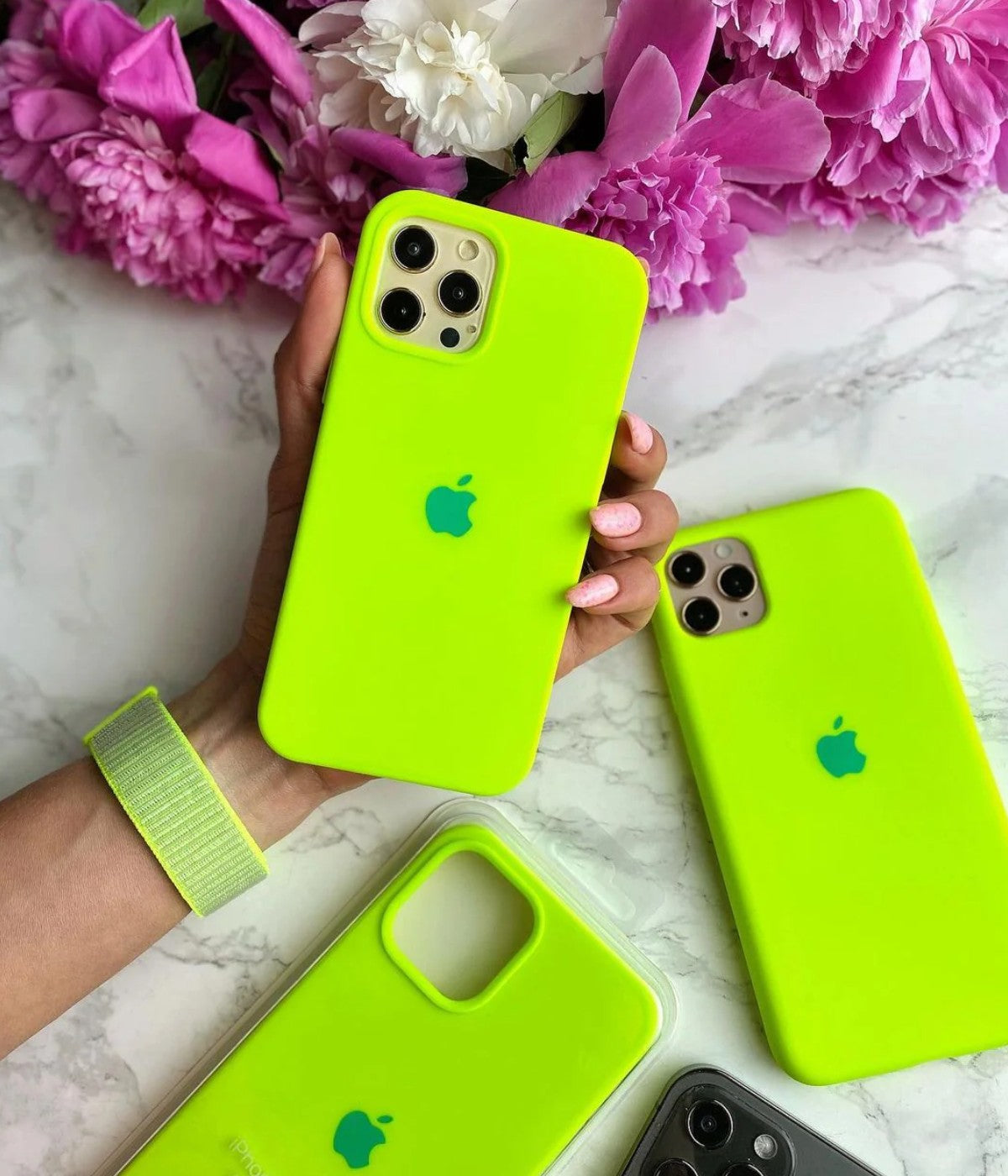 Multiple fluorescent green iPhone silicone cases on a white fabric background