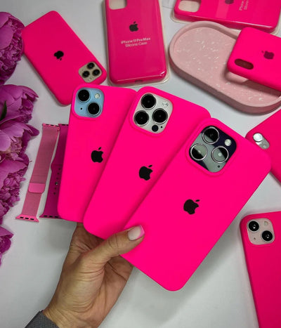 Multiple hot pink iPhone silicone cases on a white surface.