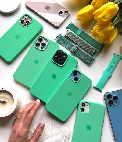 Multiple mint green iPhone silicone cases on a white fabric background