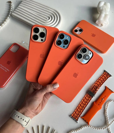 Multiple orange iPhone silicone cases on a white surface.