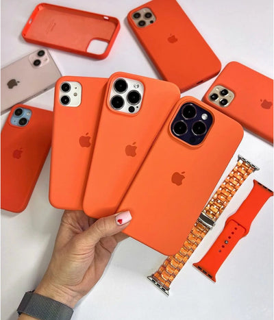 Multiple orange iPhone silicone cases on a white fabric background