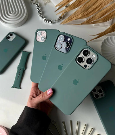Multiple pine green iPhone silicone cases on a white surface.