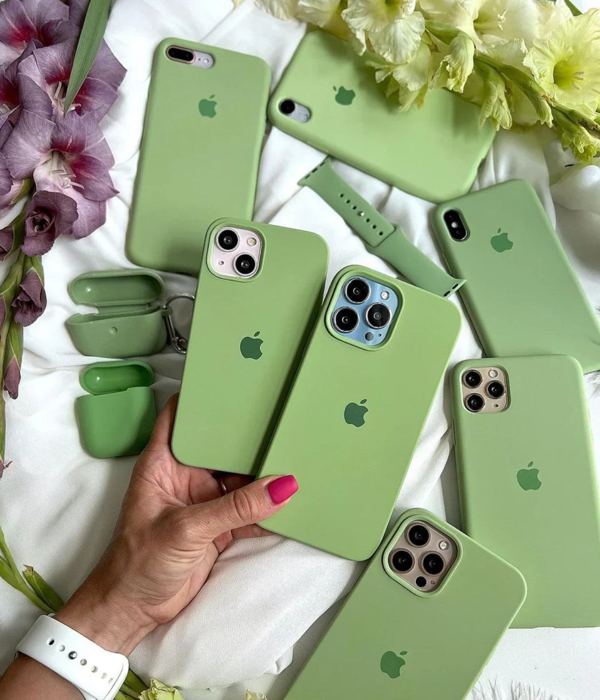 Multiple pistachio green iPhone silicone cases on a white surface.