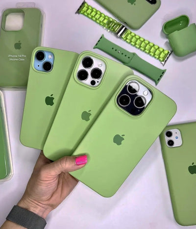 Multiple pistachio green iPhone silicone cases on a white fabric background