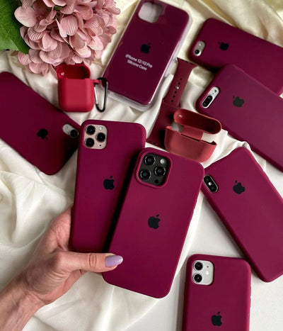 Multiple plum iPhone silicone cases on a white fabric background