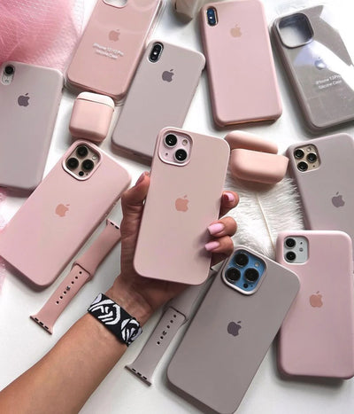 Multiple sand pink iPhone silicone cases on a white surface.