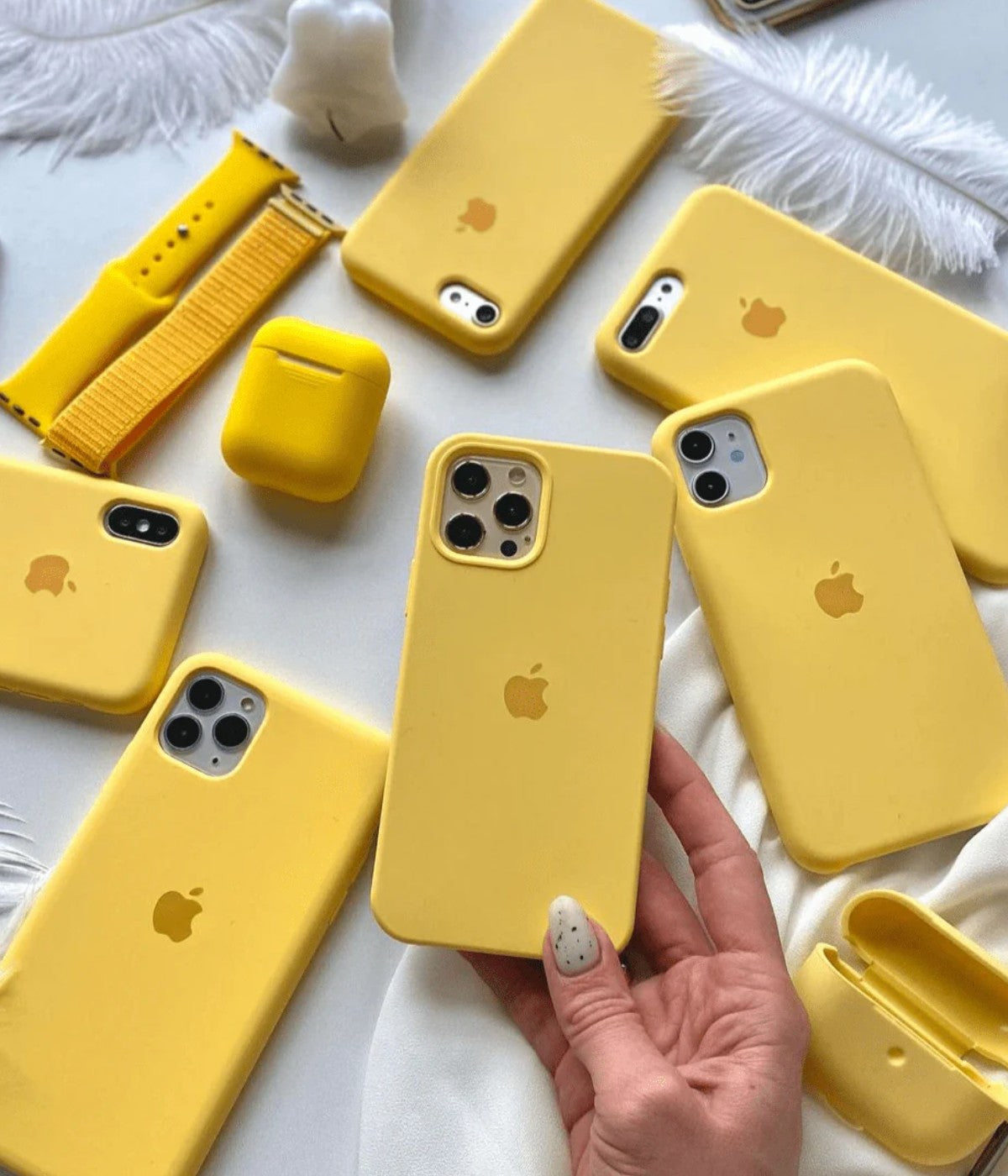 Multiple yellow iPhone silicone cases on a white surface.