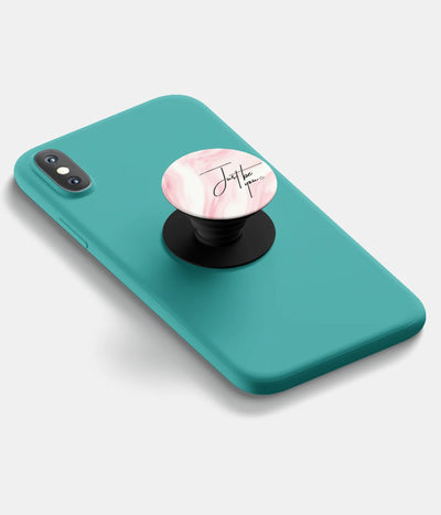 A top-down view of a phone grip holder attached to a mobile phone case on a white background