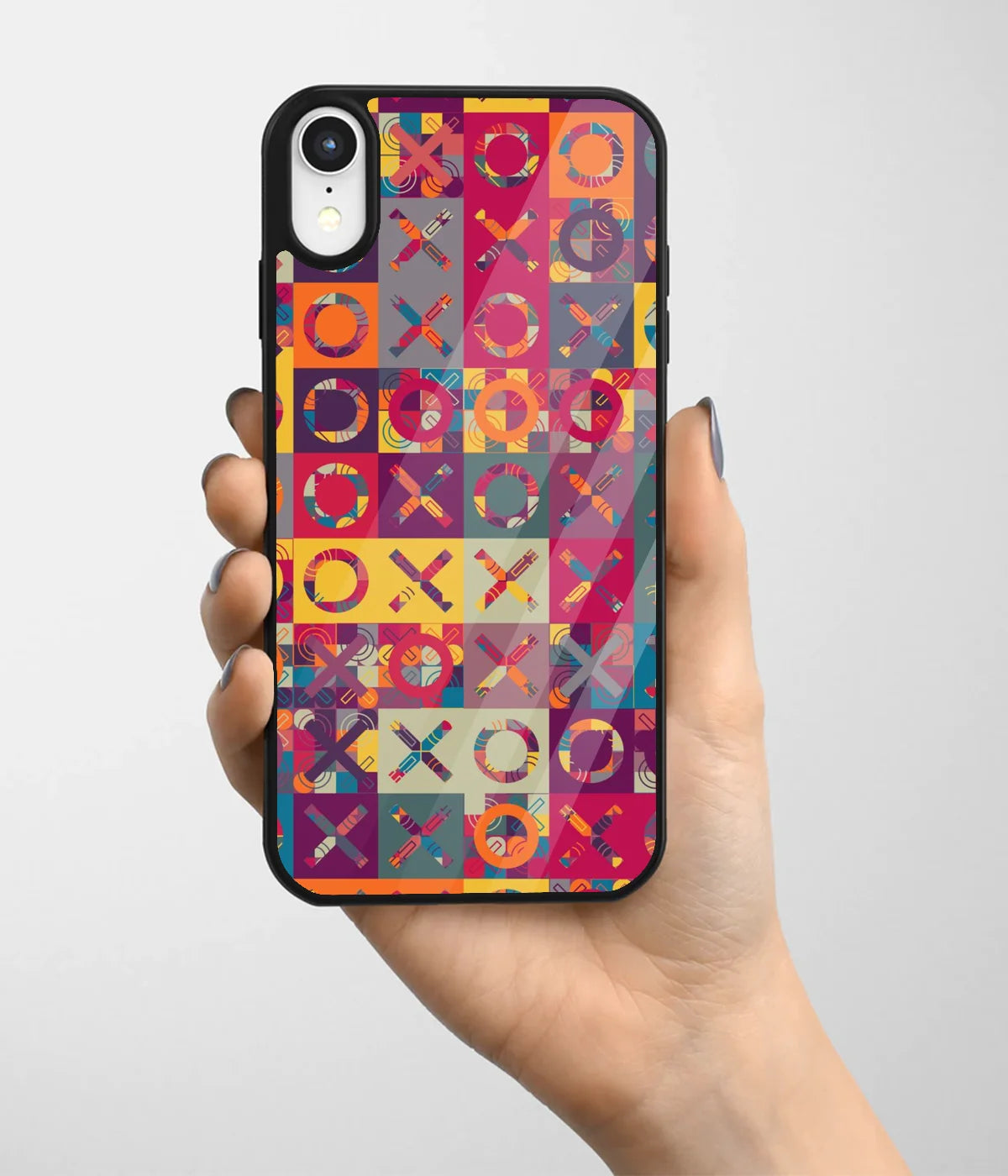 A hand holding a glass phone case with a colorful design.